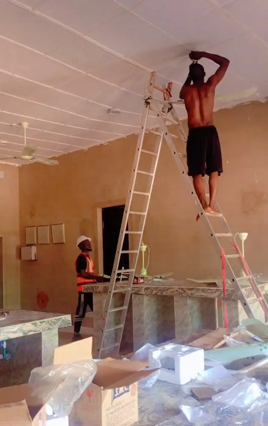 Electrician fixing a ceiling fitting from a ladder