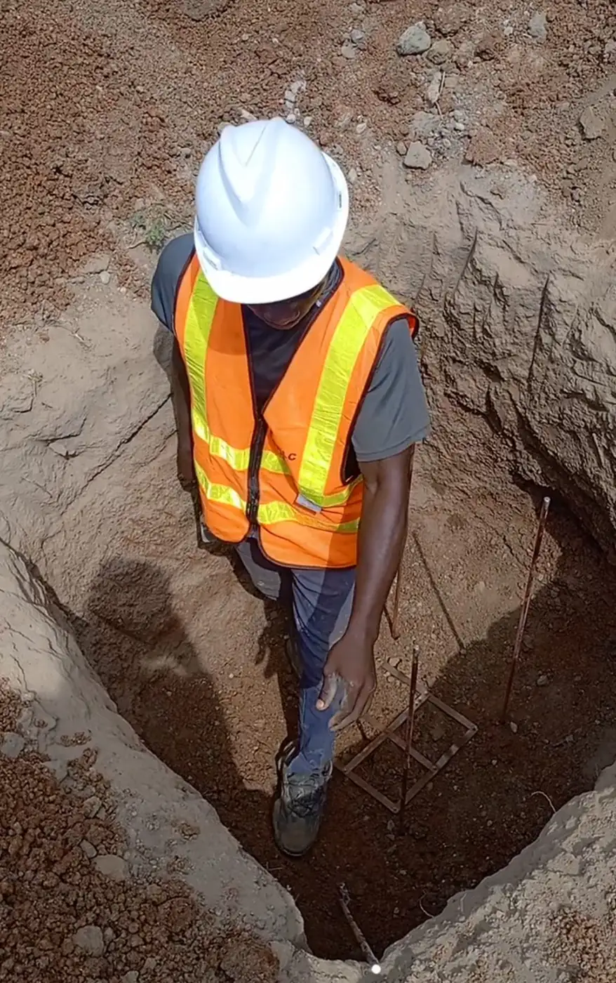 Engineer in hard hat inspecting a foundation pit